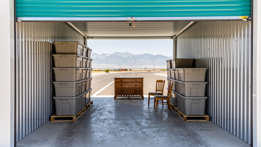 Packed storage unit with labeled bins, a walkway, and furniture set off the floor