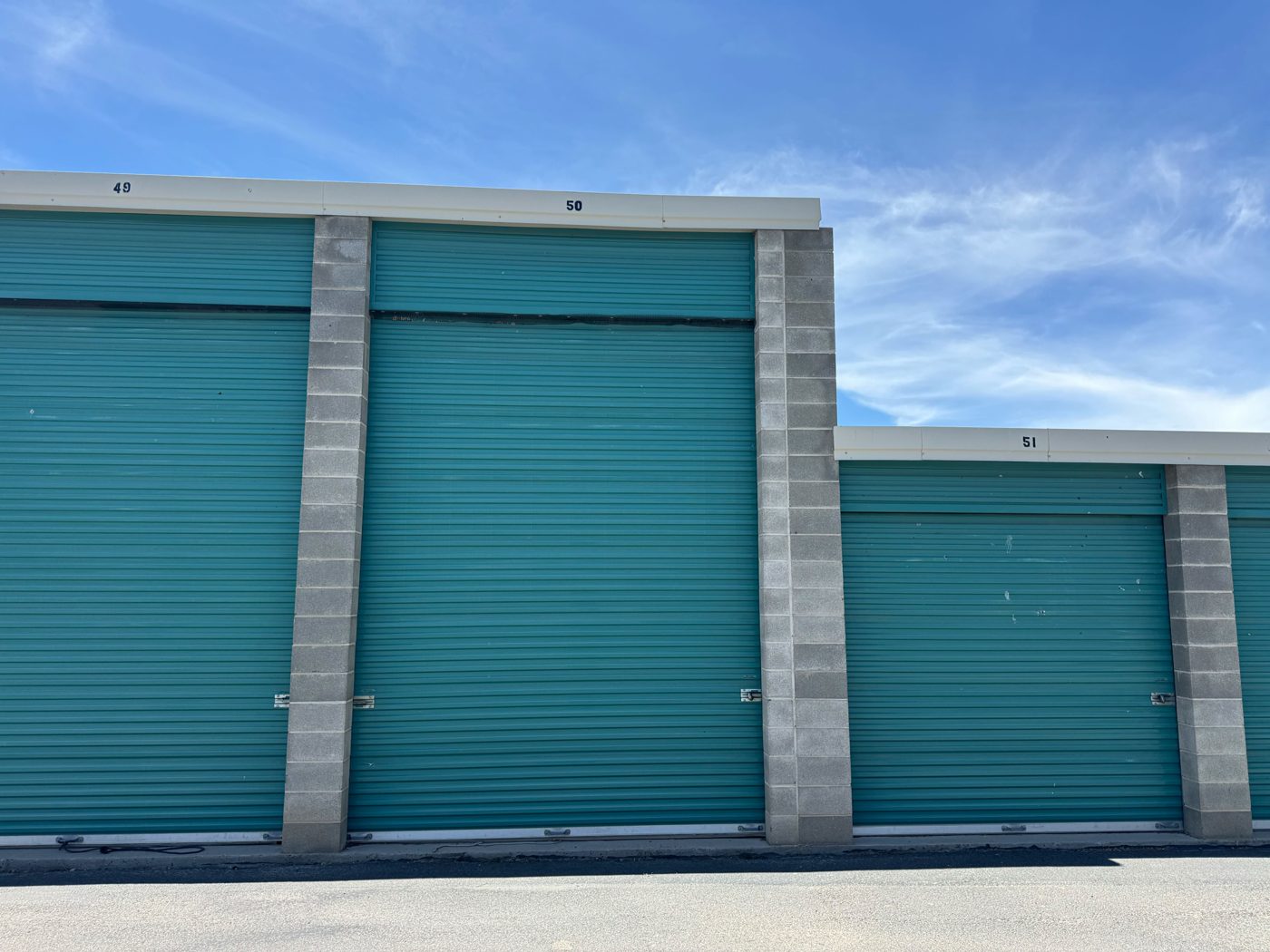 Close view of two teal roll-up doors on drive-up storage units